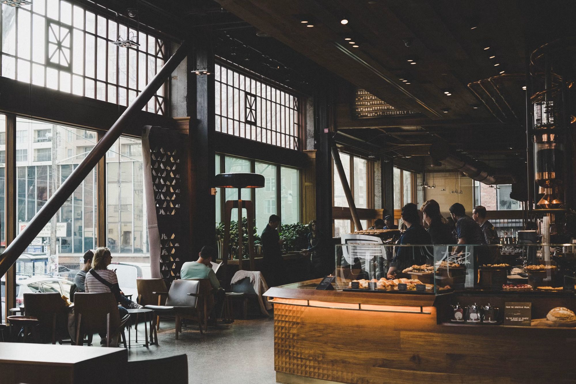 The cafe room, people at the tables under warm pendant lights