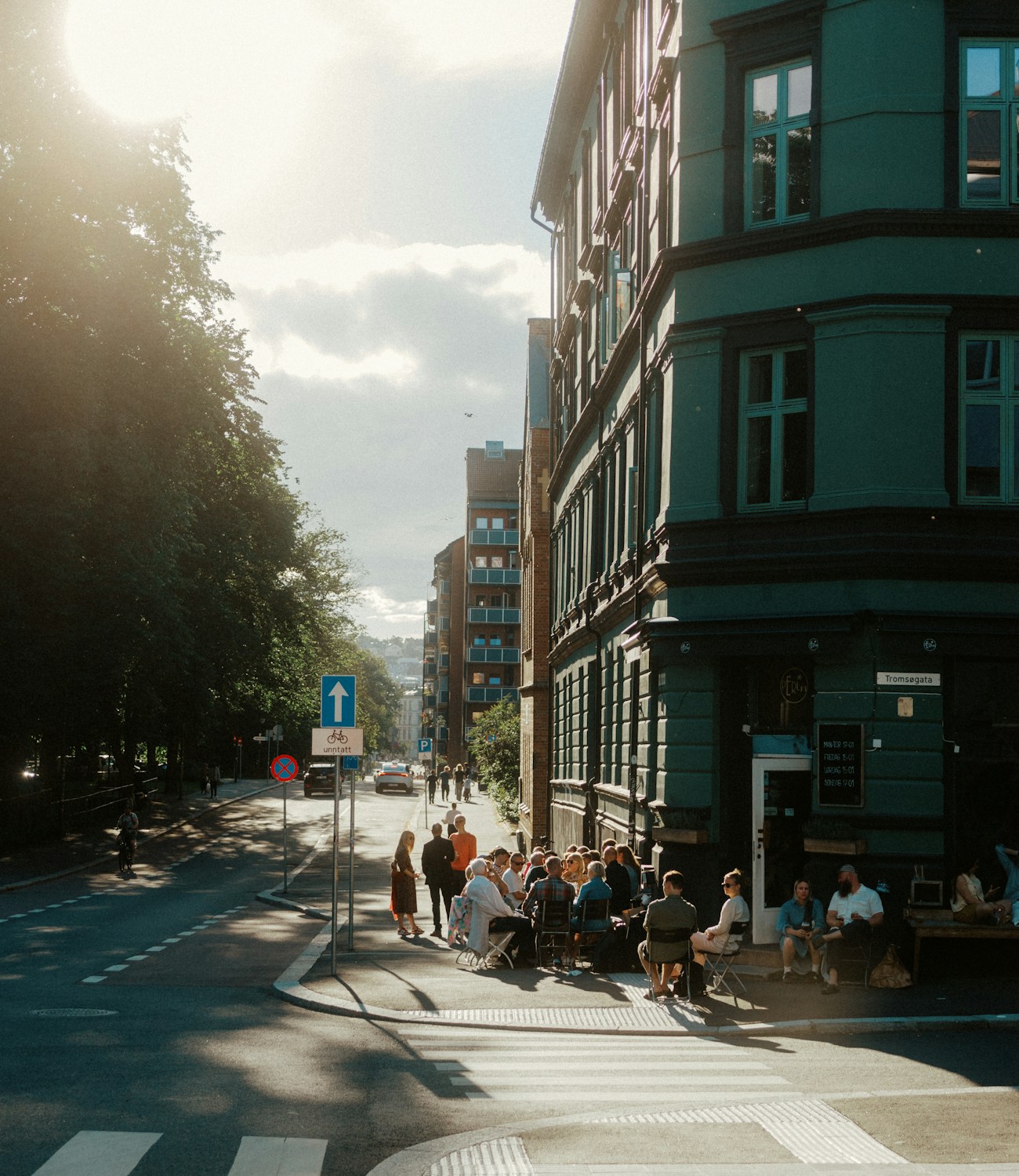 The cafe on its street corner, people at the pavement tables